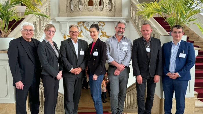 Mehrere Personen stehen in einer Reihe nebeneinander und lächeln in die Kamera