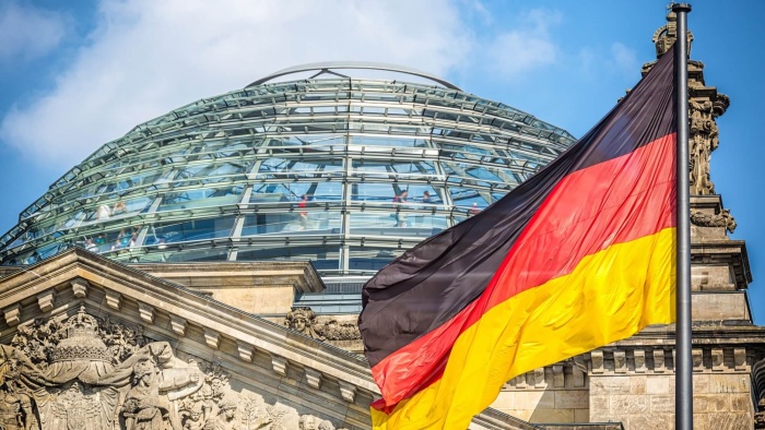 Die Reichstagskuppel mit einer wehenden Deutschlandflagge davor